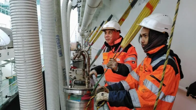 To men doing work on an LNG vessel